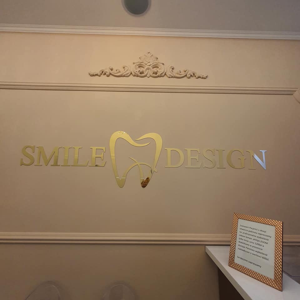 Złote godło Smile Design na ścianie recepcji gabinetu w Przemyślu